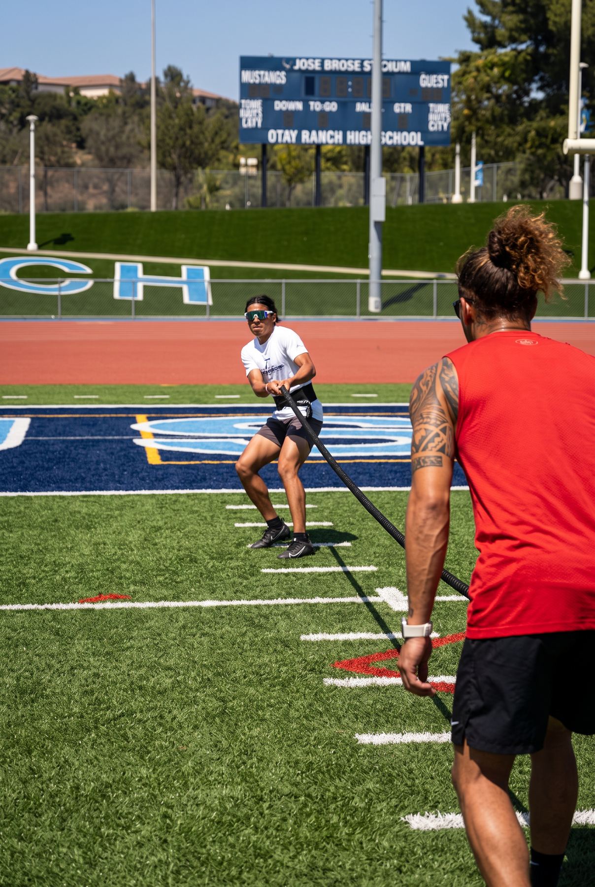 Athlete driving through a resisted sprint with band tension held by Coach Jason