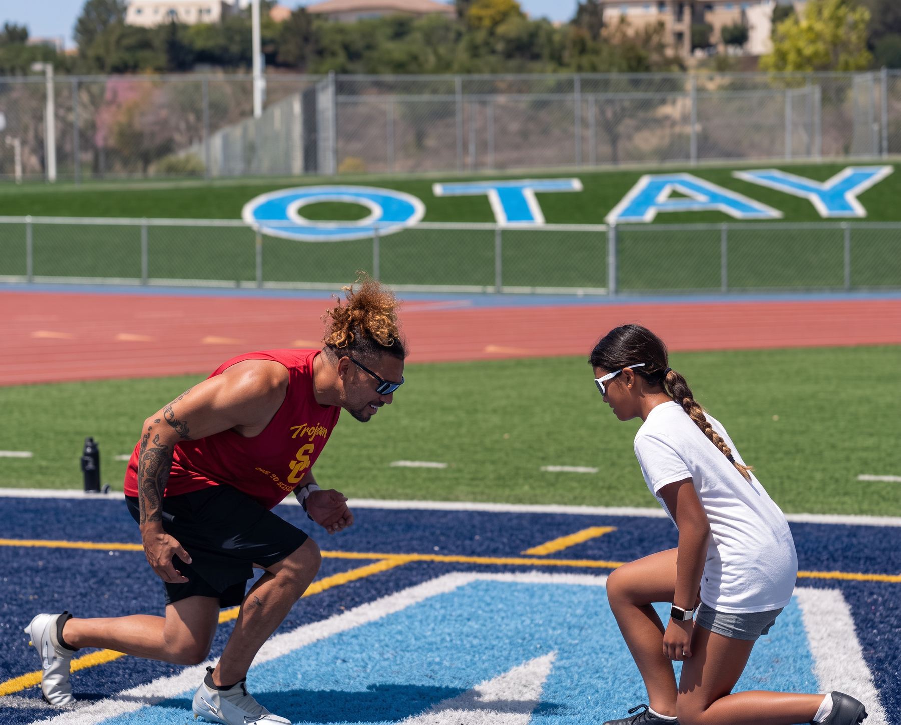 Coach Jason demonstrating first-step mechanics beside a young athlete